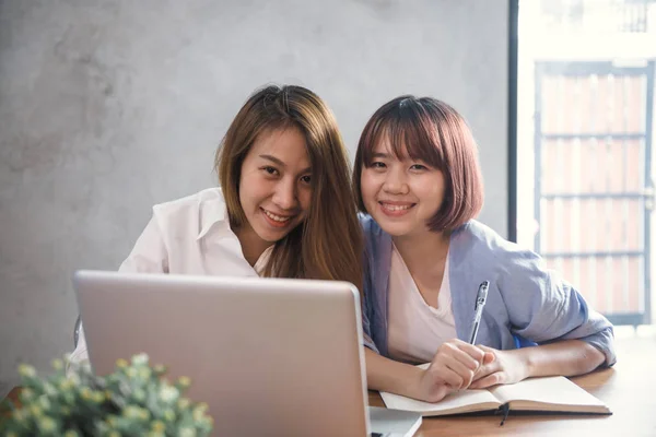 Deux jeunes femmes d'affaires assises à table dans un café. Femmes asiatiques utilisant un ordinateur portable et une tasse de café. Freelance travaillant dans un café. Travailler en dehors du bureau. Réunion en tête à tête . — Photo