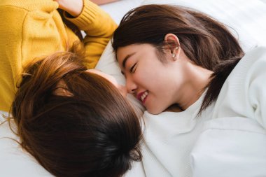 Sarılma ve yan yana evde battaniyenin altında yatakta yatarken süre gülümseyen güzel genç Asyalı kadınlar Lgbt lezbiyen mutlu çift. Komik kadın uyan sonra. LGBT lezbiyen birlikte kapalı çift kavramı.
