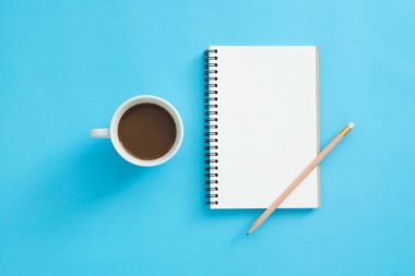 Ofis Masası adlı kullanıcının alanı - düz çalışma üstten görünüm mockup bir çalışma alanı beyaz boş defter sayfası, kahve fincanı ve dekorasyon pastel mavi zemin üzerine yatırın. Pastel mavi renk arka plan boşluk kavramı.