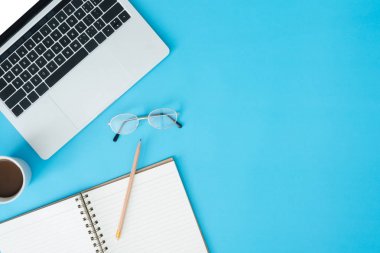 En az çalışma alanı - yaratıcı düz fotoğraf çalışma masası yatıyordu. Üstten Görünüm ofis büro dizüstü bilgisayar, dizüstü bilgisayarlar ve mavi renk arka plan üzerinde kahve fincanı. Kopya alanı, düz yatıyordu fotoğraf ile Üstten Görünüm.