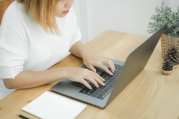 Piękna młoda uśmiechający się Asian kobieta działa na laptopie w domu, w pracy biurowej. Kobieta pracuje z domu poprzez pisania na klawiaturze komputera przenośnego. Czasu w domu. — Zdjęcie stockowe