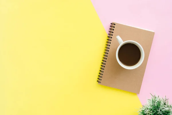 Creativo plano laico foto de escritorio del espacio de trabajo. Escritorio de oficina con vista superior con cuadernos, planta, taza de café y espacio de copia sobre fondo de color pastel. Vista superior con espacio de copia, fotografía plana . — Foto de Stock