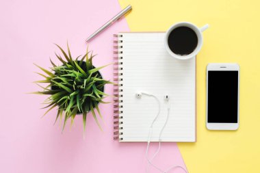 Ofis Masası çalışma alanı - düz beyaz boş dizüstü bilgisayar, kulaklık, kahve fincanı ve sahte telefon pastel arka plan üzerinde çalışma alanının en iyi görünümü yatırın. Pastel pembe sarı renk arka plan boşluk kavramı
