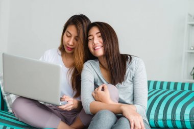 Güzel genç Asyalı kadınlar Lgbt lezbiyen mutlu çift kanepe online satın alma üzerinde oturan evde oturma odasında dizüstü bilgisayar kullanarak. LGBT lezbiyen birlikte kapalı kavramı çift. Evde güzel vakit.