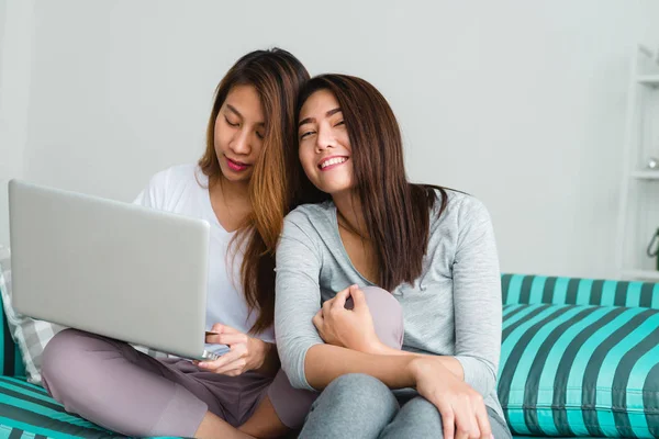 Belles jeunes femmes asiatiques LGBT lesbienne couple heureux assis sur le canapé acheter en ligne en utilisant un ordinateur portable dans le salon à la maison. LGBT couple lesbien ensemble concept intérieur. Passer du bon temps à la maison . — Photo