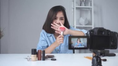 Asyalı kadın ya da güzellik blogger ile fırça ve video kaydı ve evde el sallayarak kamera gülümseyen mutlu. Güzellik videoblog bloglama insanlar kavramı. Dolly vurdu.