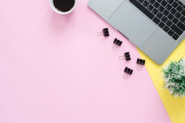 Ofis Resepsiyon çalışma alanı - düz dizüstü bilgisayar, bir fincan kahve ve pastel arka plan üzerine yerleştirerek küçük çim üstten görünüm kopya alanı çalışma alanı yatırın. Pastel pembe sarı renk arka plan boşluk kavramı.