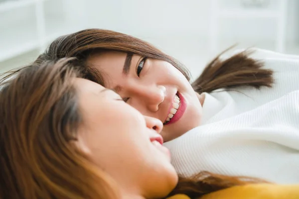 Wanita Asia muda yang cantik pasangan lesbian LGBT berpelukan dan tersenyum sambil berbaring di tempat tidur di bawah selimut di rumah. Wanita lucu setelah bangun. LGBT lesbian pasangan bersama-sama dalam ruangan konsep . — Stok Foto