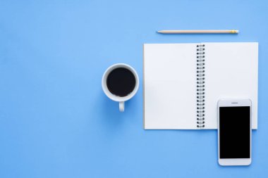 Ofis Masası adlı kullanıcının alanı - düz çalışma üstten görünüm mockup bir çalışma alanı beyaz boş defter sayfası, kahve fincanı ve telefon pastel mavi zemin üzerine yatırın. Pastel mavi renk arka plan boşluk kavramı.