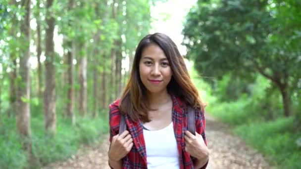 幸せな若いアジア女性旅行者のバックパックを森を歩きます ハイカーのバックパックを夏の森でパス上を歩くアジアの女性 冒険バックパッカー旅行の人々 の概念 — ストック動画