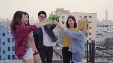 Genç Asyalı kadınlar ve dans ve hava çatıda günbatımı kentsel partide dj tarafından oynanan müzik kollarında kadar yükselterek insanlar grubudur. Genç Asyalı kız ve erkek arkadaş içecekler ile takılmak
