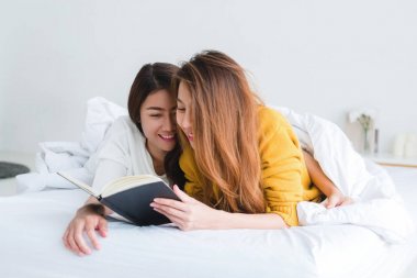 Kitap yan yana evde battaniyenin altında yatakta yatarken okumak güzel genç Asyalı kadınlar Lgbt lezbiyen mutlu çift. LGBT lezbiyen birlikte kapalı kavramı çift. Evde güzel vakit.