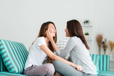 Sarılma ve birlikte gülümseyen evde oturma odasında kanepede oturan güzel genç Asyalı kadınlar Lgbt lezbiyen mutlu çift. LGBT lezbiyen birlikte kapalı kavramı çift. Evde güzel vakit.