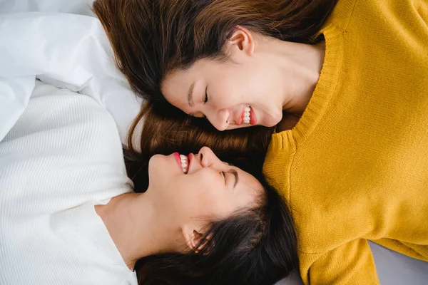 Belles jeunes femmes asiatiques LGBT lesbienne couple heureux étreignant et souriant tout en étant couché ensemble dans le lit sous couverture à la maison. Des femmes drôles après le réveil. LGBT couple lesbien ensemble à l'intérieur concept . — Photo