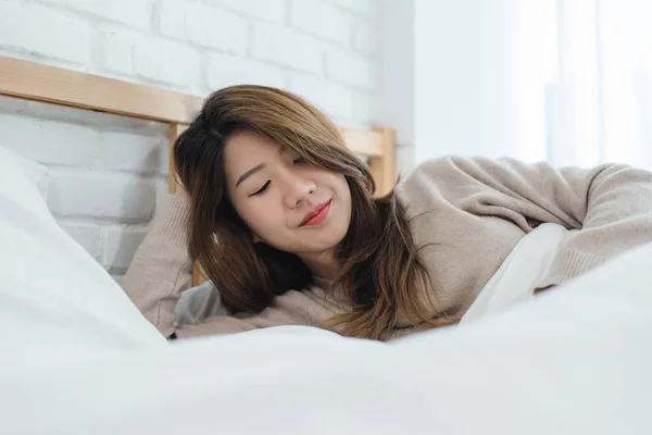 Portrait beautiful young Asian woman on bed at home in the morning. Cheerful Asian woman wearing a comfortable sweater and smiling on her bed. Relaxing room. lifestyle asia woman at home concept. — Stock Photo, Image