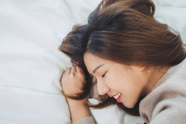 Retrato hermosa mujer asiática joven en la cama en casa por la mañana. Mujer asiática alegre usando un suéter cómodo y sonriendo en su cama. Sala de relajación. estilo de vida mujer asiática en casa concepto . —  Fotos de Stock