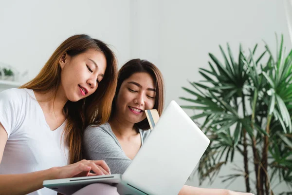 Belle giovani donne asiatiche lesbiche LGBT felice coppia seduta sul divano acquistare online utilizzando un computer portatile e carta di credito in soggiorno a casa. LGBT coppia lesbica insieme indoor concetto . — Foto Stock