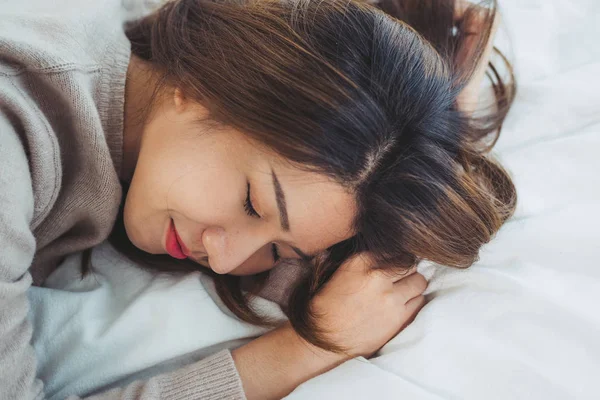 Wanita Asia muda yang cantik tidur di tempat tidur di pagi hari. Gadis asia yang menarik menggunakan waktu tidur di kamar tidurnya yang nyaman. Kamar tidur santai. Lifestyle asia woman at home concept . — Stok Foto