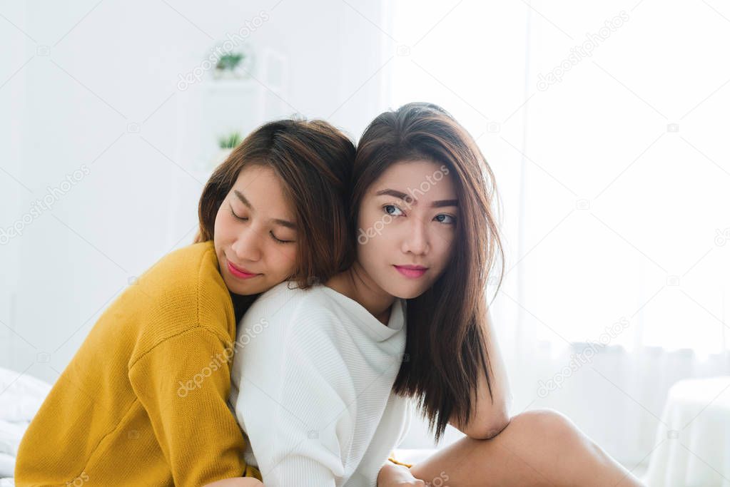 Beautiful young asian women LGBT lesbian happy couple sitting on bed hugging and smiling together in bedroom at home. LGBT lesbian couple together indoors concept. Spending nice time at home.