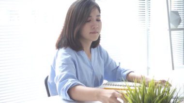 Yavaş hareket - oturma odasında evde sıcak kahve içme tadını çıkarırken dizüstü bilgisayarda çalışan güzel genç gülümseyen kadın. Evde zaman zevk. Ev ofisinde çalışan Asya iş kadın