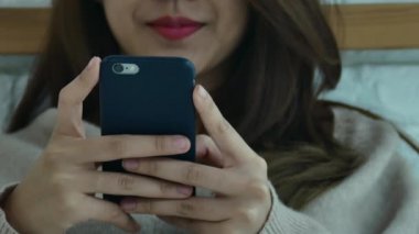 Mutlu Asyalı kadınlar akıllı telefon sabah yatakta kullanıyorsunuz. Asyalı kadın yatakta smartphone ile sosyal uygulamalar kontrol. Gülümseyen kadın evde cep telefonu ile net sörf. Telefon bağımlısı kavramı. 