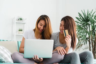 Güzel genç Asyalı kadınlar Lgbt lezbiyen mutlu çift kanepe online satın alma üzerinde oturan evde oturma odasında dizüstü bir bilgisayar ve kredi kartı kullanarak. LGBT lezbiyen birlikte kapalı çift kavramı.