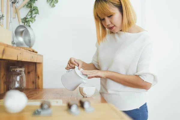 Houkutteleva kaunis aasialainen nainen nauttii lämmintä kahvia keittiössä kotonaan. Aasialainen nainen yllään mukava pusero tilalla kuppi kahvia. elämäntapa Aasia nainen kotona käsite . — kuvapankkivalokuva