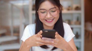 Ofiste cep telefonu kullanan serbest Asyalı kadınlar. Genç Japon Asyalı kız akıllı telefon kullanıyor. Sosyal medyayı kontrol ediyor. İş yeri konseptinde masada..