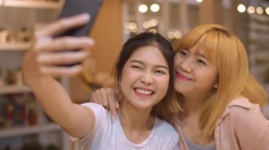 Neşeli genç Asyalı arkadaş bir kafede cep telefonu kullanarak selfie çekiyor. Restoranda ya da kafede birlikte iki çekici Asyalı kız. Tatil aktivitesi, ya da modern yaşam tarzı konsepti.