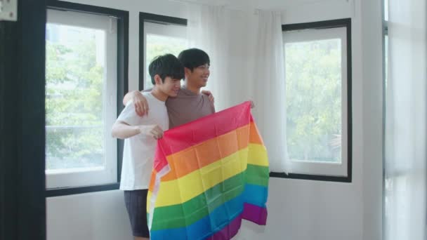 年轻的亚洲男同性恋夫妇在家里很高兴地展示彩虹旗 — 图库视频影像
