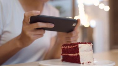 Blogger Asyalı arkadaş canlısı kadın etkileyicisi gece kafeteryasında pasta yiyor. Güzel genç bayan, rahatla. Teknoloji cep telefonu kullanarak rahatla. Üniversite kampüsünde sosyal medyada yemek yüklerken fotoğrafını çek..