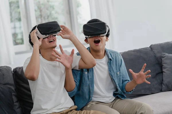 Jovem Asiático casal gay usando a tecnologia engraçada em casa, Ásia amante cara lgbtq + sentindo-se feliz diversão e realidade virtual, VR jogar jogos juntos enquanto deitado sofá na sala de estar em casa conceito . — Fotografia de Stock