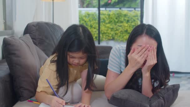 アジア系の中年女性は娘に宿題を教え 家で絵を描く ライフスタイルの母親と子供の幸せ楽しい夜のコンセプトで現代の家のリビングルームで一緒に時間を過ごす — ストック動画