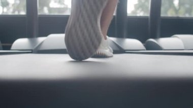 Spor ayakkabısı giymiş genç Asyalı adam spor salonunda koşu bandında yağ yakma egzersizi yapıyor. Sporcu eğlencesi, kardiyo eğitimi, spor yapan insanlar, sağlıklı yaşam tarzı..