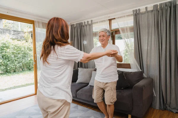 Asijské starší páry tančí spolu, zatímco poslouchat hudbu v obývacím pokoji doma, sladký pár vychutnat milostný moment, zatímco se baví, když odpočívá doma. Životní styl senior rodina relaxovat doma koncept. — Stock fotografie