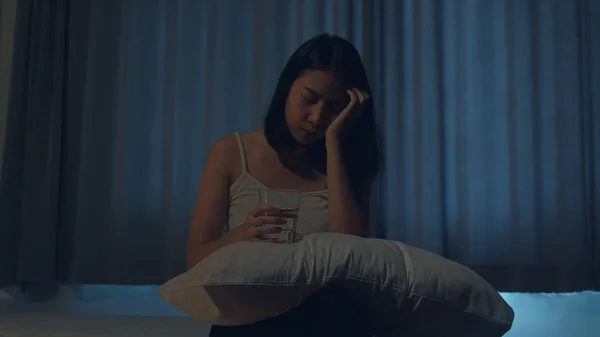 Beautiful Asian young woman sitting on bed take sleeping pill or night medicine in bedroom. Unhealthy sick Indian female suffers from insomnia or headache, depressed girl holds antidepressant meds. — Stock Photo, Image