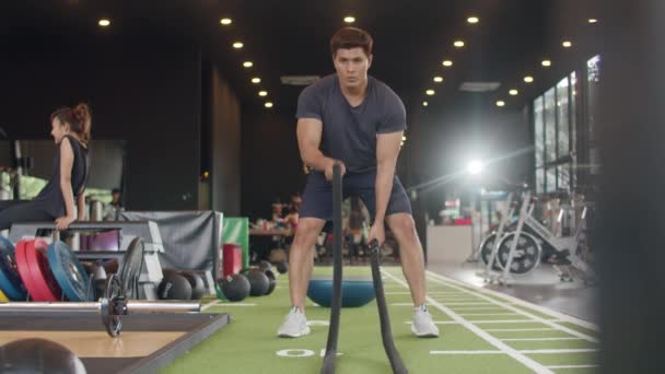 年轻的运动员是亚洲人 在健身演播室里用钢丝绳进行脂肪燃烧锻炼时 他是以波浪运动的方式移动钢丝绳的 运动员娱乐活动 健康生活方式概念 — 图库视频影像