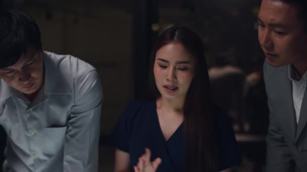 Millennial Asia business men and business women meeting brainstorming ideas about new paperwork project colleagues working together planning success strategy enjoy teamwork in small modern night office.