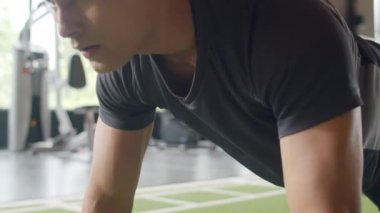 Yakışıklı genç atlet Asyalı adam fitness sınıfında şınav çekerek yağ yakma egzersizi yapıyor. Sporcu eğlencesi, fonksiyonel eğitim, spor yapan insanlar, sağlıklı yaşam tarzı konsepti..