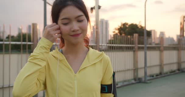 年轻美丽的亚洲女运动员在城市跑步时 用智能手机听音乐 一大早 韩国少女穿着运动服在走道桥上 — 图库视频影像