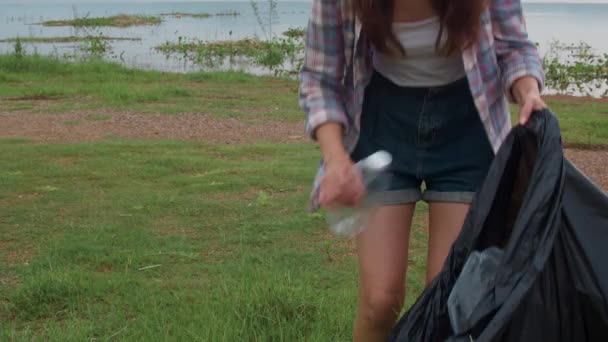 快乐的年轻的亚洲积极分子在海滩上收集塑料垃圾 韩国女性志愿者帮助保持自然清洁和捡垃圾 环境保护及污染问题的概念 — 图库视频影像