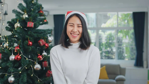 Asian women celebrate Christmas festival. Female teen wear Christmas hat relax happy smiling looking at camera enjoy xmas winter holidays together in living room at home.