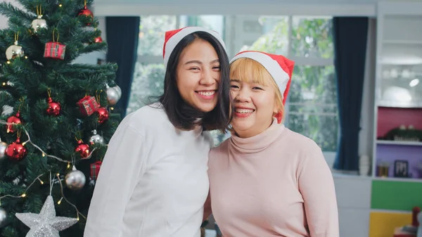 Asiatique Lesbienne couple célébrer Noël festival. LGBTQ adolescent féminin porter chapeau de Noël se détendre heureux sourire en regardant la caméra profiter de Noël vacances d'hiver ensemble dans le salon à la maison . — Photo