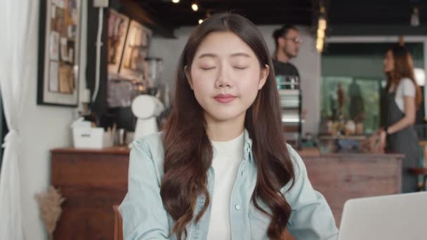コーヒーショップで幸せな気分で目を覚ますポートレート若いアジアのフリーランス女性 魅力的な日本のビジネスマンの女性は 都会のカフェやレストランでカメラを探しておもちゃの笑顔をリラックスラップトップで — ストック動画