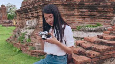 Gezgin Asyalı kadın fotoğraf çekmek için Ayutthaya, Tayland 'da tatil gezisi yaparken fotoğraf çekiyor. Japon bayan turist, geleneksel kentteki muhteşem şehir simgesinde yolculuğunun tadını çıkarıyor. Yavaş çekim.