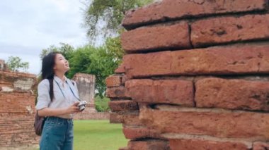 Gezgin Asyalı kadın fotoğraf çekmek için Ayutthaya, Tayland 'da tatil gezisi yaparken fotoğraf çekiyor. Japon bayan turist, geleneksel kentteki muhteşem şehir simgesinde yolculuğunun tadını çıkarıyor. Yavaş çekim.