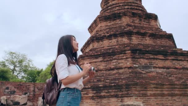 タイのアユタヤで休暇を過ごしながら写真を撮るためにカメラを使用している旅行者アジアの女性 日本の女性観光客は 伝統的な街の素晴らしいランドマークで彼女の旅をお楽しみください スローモーション — ストック動画