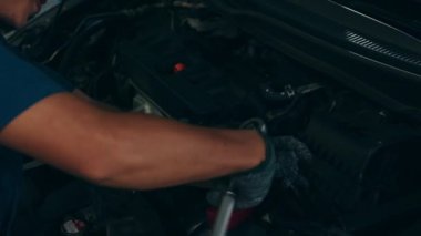 Araba tamircisinin tamir istasyonunda kaldırılan otomobilin motoruyla ilgili detaylar. Geceleri tamirci garajında araba tamir eden Asyalı yetenekli bir adam. 4k ağır çekim.