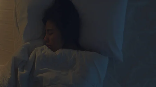 Nervosa giovane donna asiatica che ha un incubo sdraiato sul letto nella sua camera da letto a casa nel cuore della notte. Soffre di mal di testa o emicrania, insonnia, apnea del sonno o concetto di stress. Foto vista dall'alto . — Foto Stock