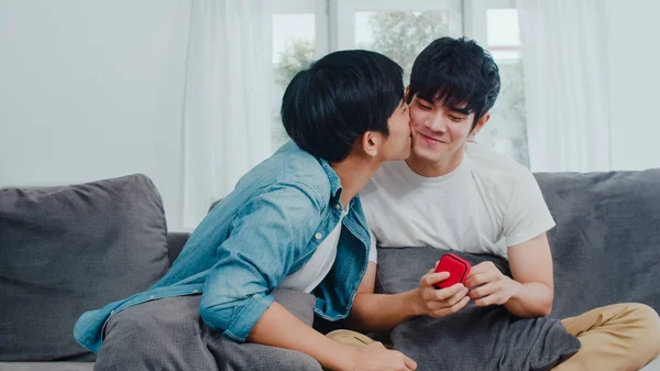 Nuori aasialainen homo pari ehdottaa kotona, teini-Korealainen LGBTQ + miehillä onnellinen hymyilevä on romanttista aikaa, kun taas ehdottaa ja avioliitto yllätys kulumista vihkisormus olohuoneessa talossa käsite . — kuvapankkivalokuva